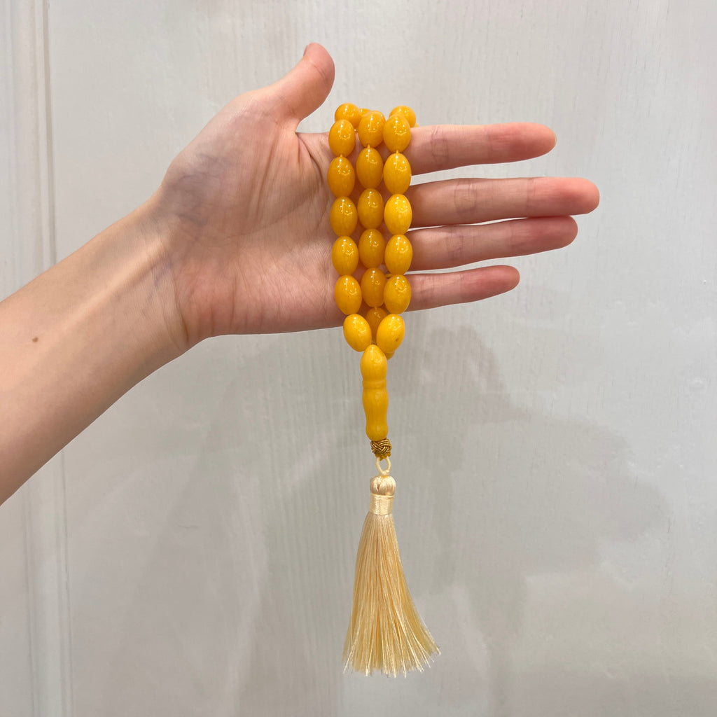 Golden amber-tone 33-bead Tasbih shown in hand for scale