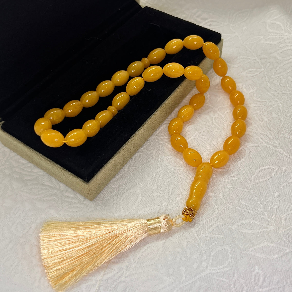Golden amber-tone 33-bead Tasbih displayed with cream tassel